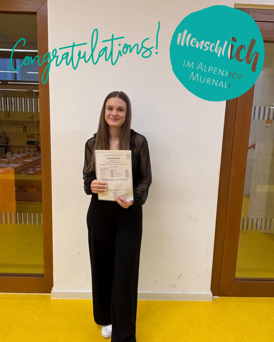 Junge Frau hält stolz ihr Abschlusszeugnis in den Händen, daneben Schriftzug „Congratulations“ und Logo „Menschlich im Alpenhof Murnau“